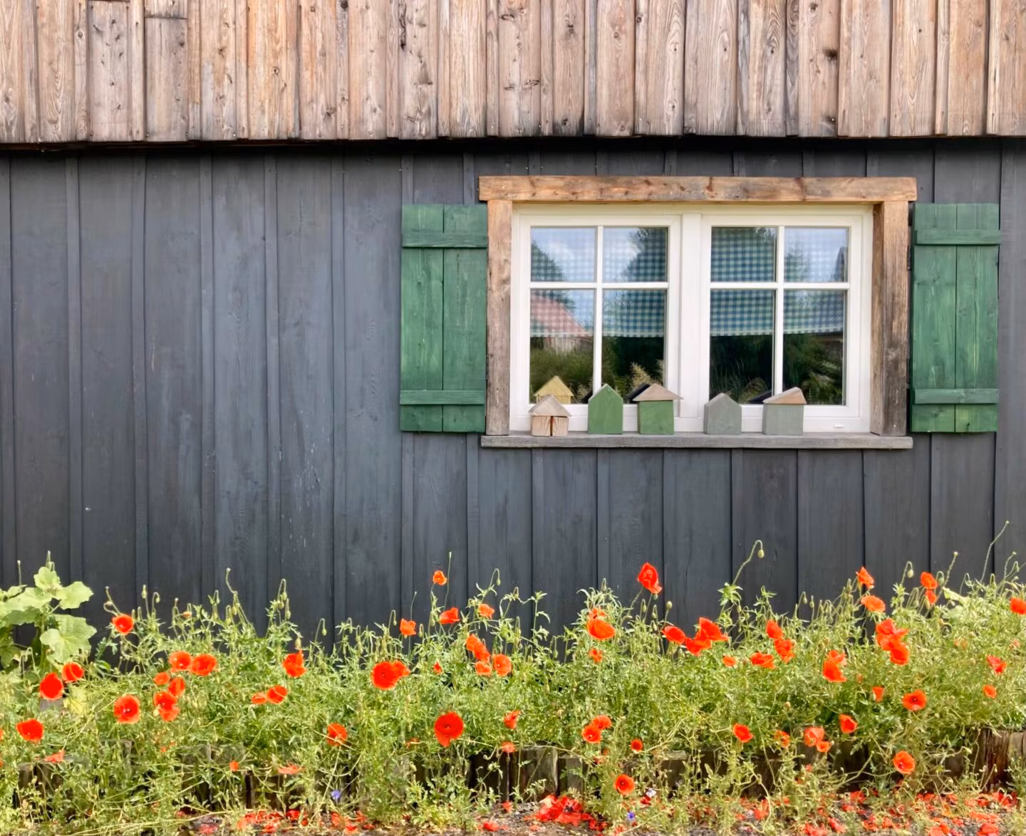 Okno drewnianego domu z czerwonymi kwiatami