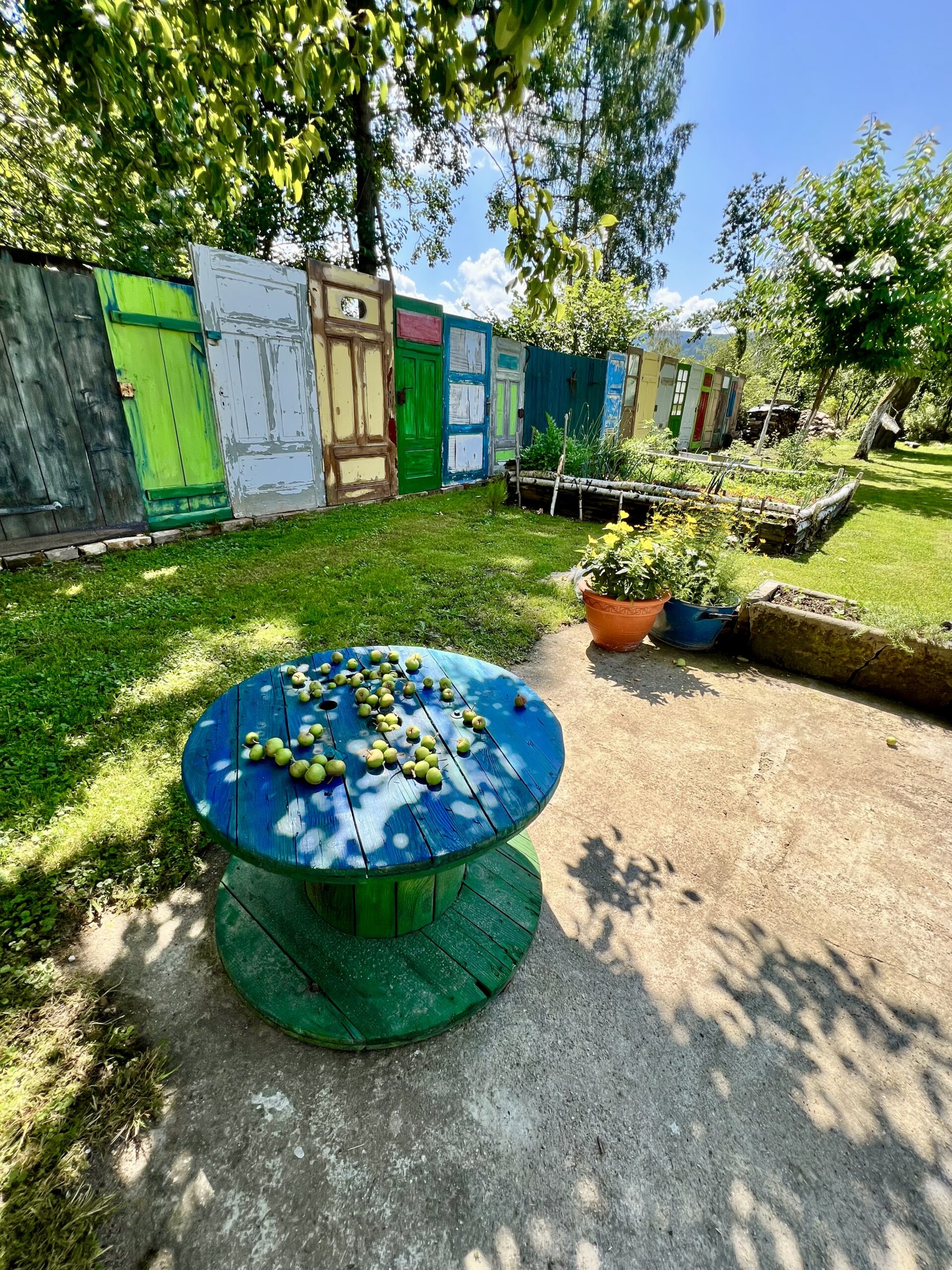 Kolorowe drzwi, niebieski stół, zielony ogród.