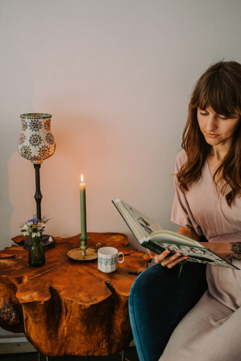 Kobieta czytająca książkę przy świecy