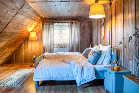 Przytulna sypialnia z drewnianymi ścianami i łóżkiem