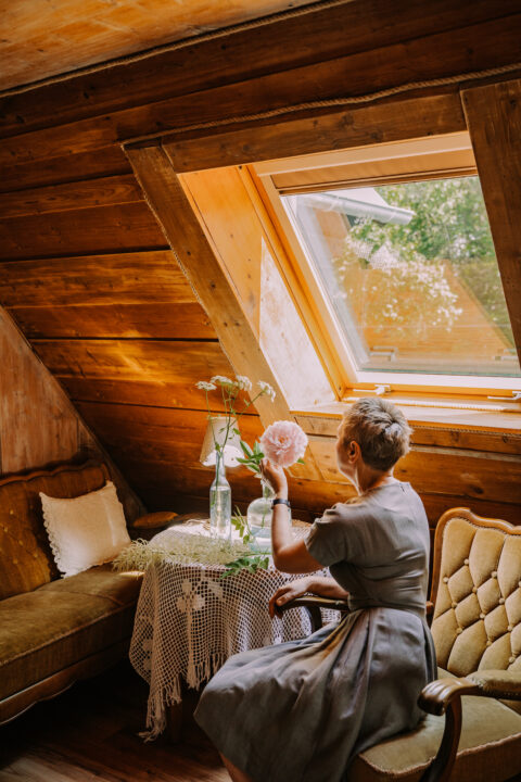 Kobieta przy oknie w drewnianym pokoju.