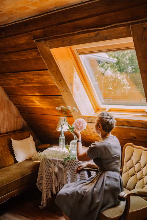 Kobieta przy oknie w drewnianym pokoju.