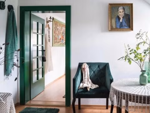 Wnętrze z zielonymi drzwiami i fotelem.