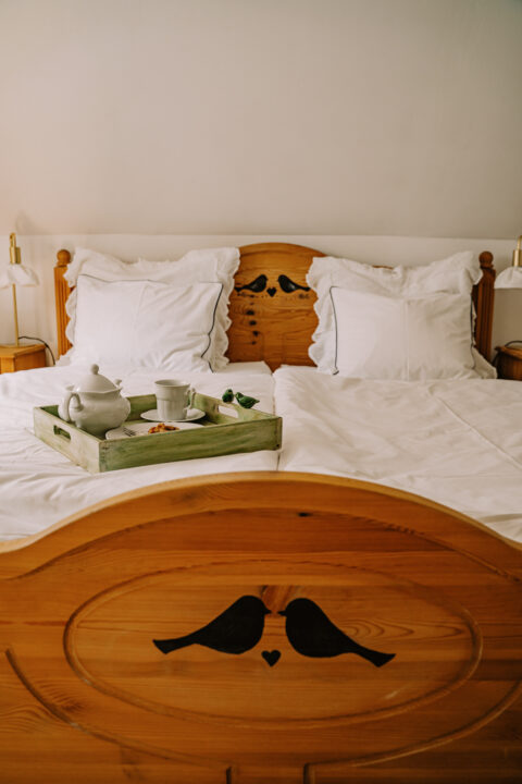 Drewniane łóżko z tacą śniadaniową na pościeli.