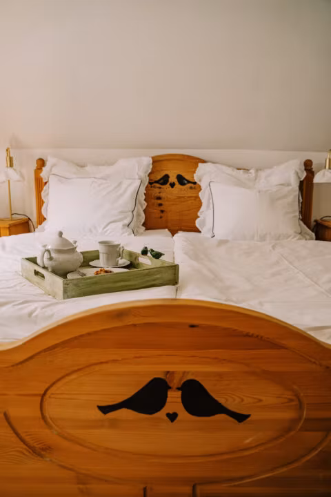 Drewniane łóżko z tacą śniadaniową na pościeli.