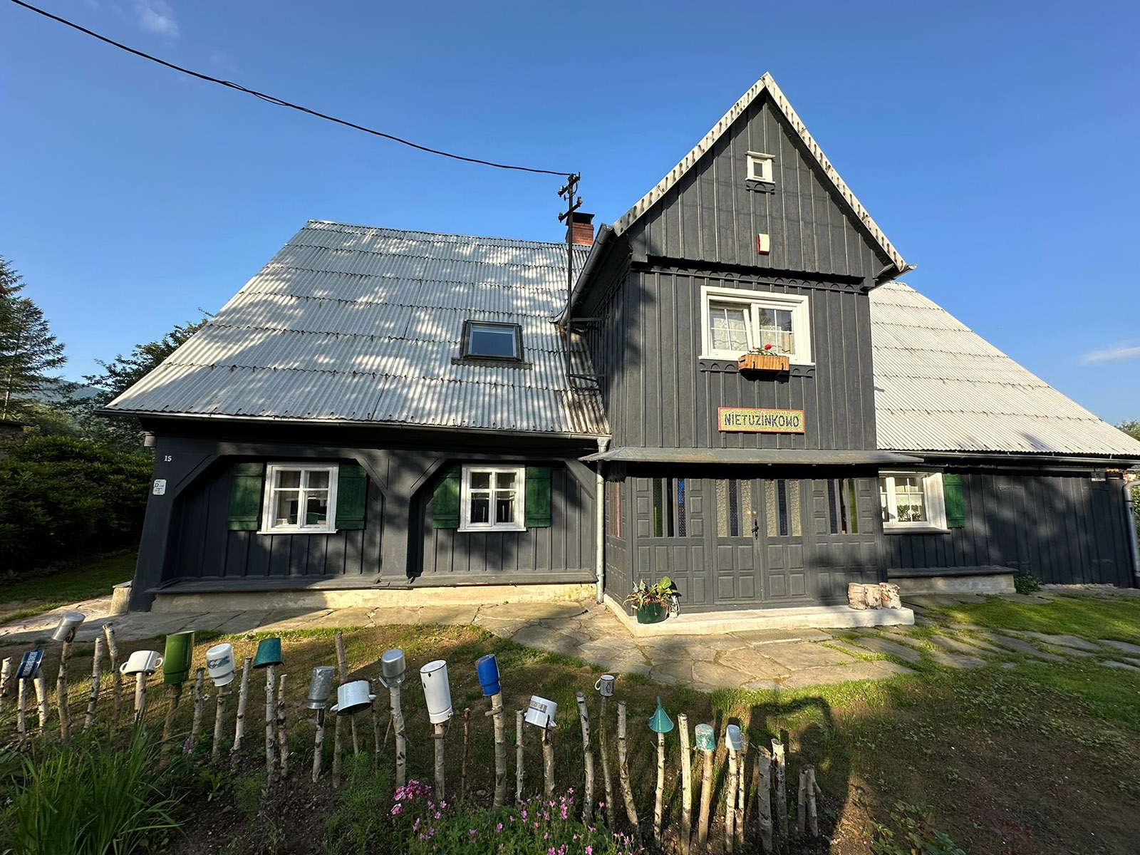 Drewniany dom z emaliowanymi kubkami na płocie