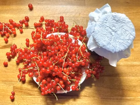 Czerwone porzeczki i słoik na drewnianym stole