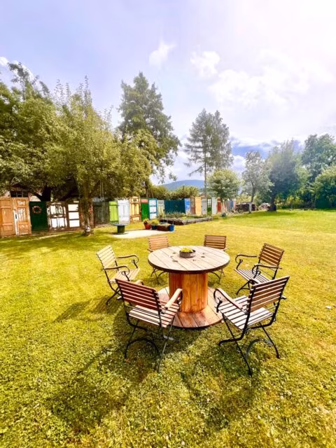 Drewniany stół i krzesła na trawie w ogrodzie.