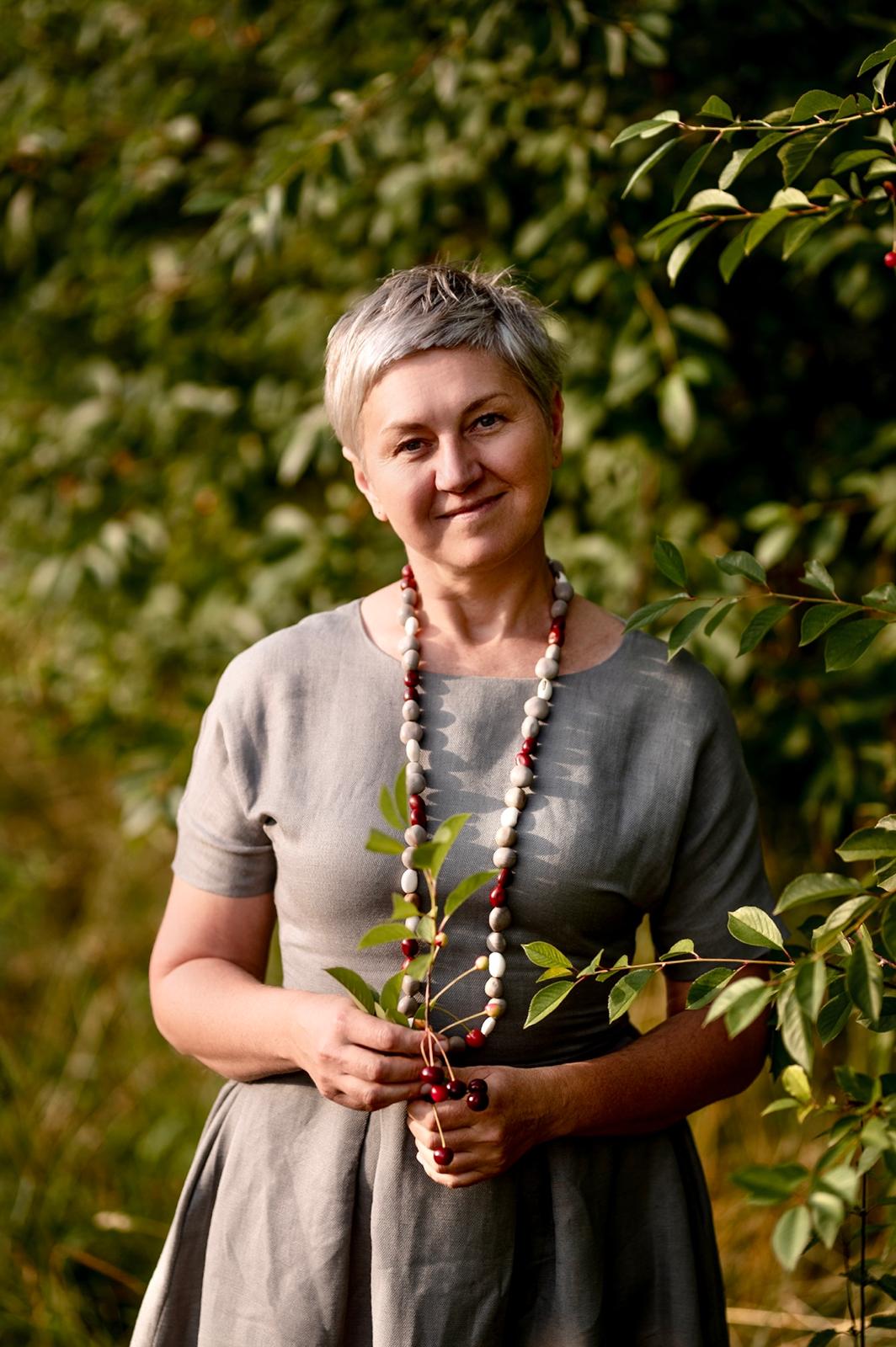 Kobieta w szarej sukience na tle liści